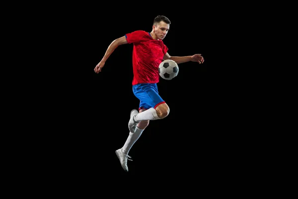 Young Caucasian soccer football player practicing isolated on black background. — Stock Photo, Image