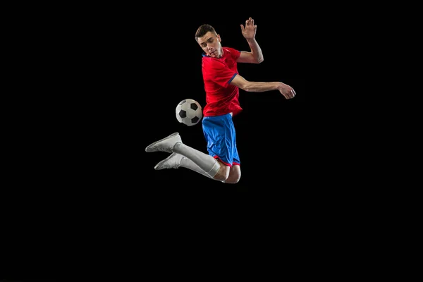 Ung kaukasisk fotboll spelare öva isolerad på svart bakgrund. — Stockfoto