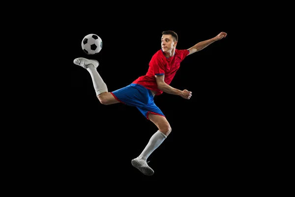 Mladý kavkazský fotbalista cvičit izolované na černém pozadí. — Stock fotografie