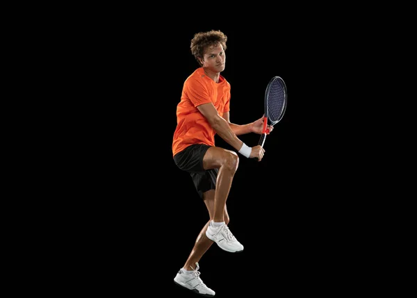 Young Caucasian man, professional tennis player training on black background. — Stock Photo, Image