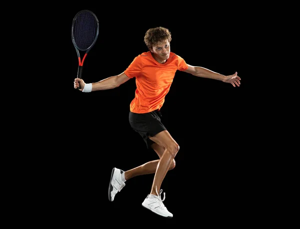 Junger kaukasischer Mann, professioneller Tennisspieler, der auf schwarzem Hintergrund trainiert. — Stockfoto