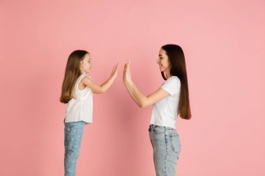 İki mutlu insan, anne ve kızı pembe arka planda izole edilmiş..
