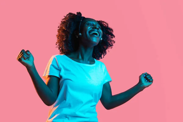Młody piękny szczęśliwy Afroamerykanin dziewczyna izolowane na różowym tle w neon. — Zdjęcie stockowe