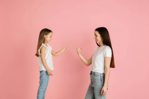 Young woman and girl, mother and daughter isolated over pink background. — Stock Photo, Image