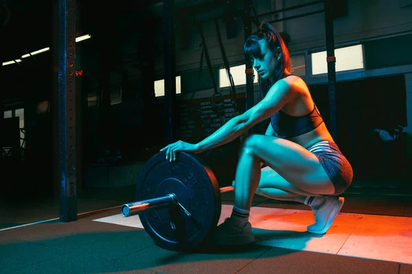 Mujer atlética joven, entrenamiento de instructor de fitness en gimnasio con luz de neón mixta. — Foto de Stock