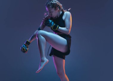 Genç bayan dövüş sanatları eğitimi mavi arka planda, neon ışıkta izole edilmiş.