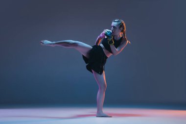 Genç bayan dövüş sanatları eğitimi mavi arka planda, neon ışıkta izole edilmiş.