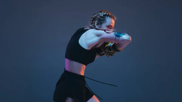 Joven mujer MMA entrenamiento de combate aislado sobre fondo azul en luz de neón — Foto de Stock