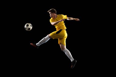 Genç adam, erkek futbolcu eğitimi siyah arka planda izole edilmiş..