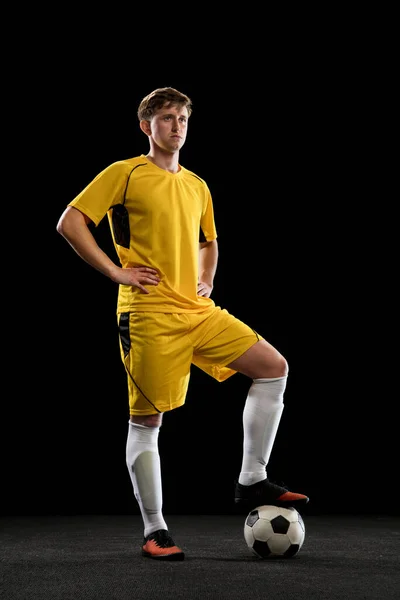 Porträt eines jungen Fußballers posiert isoliert auf schwarzem Hintergrund. — Stockfoto