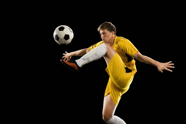 Giovane uomo, calciatore di calcio maschile formazione isolato su sfondo nero. — Foto Stock