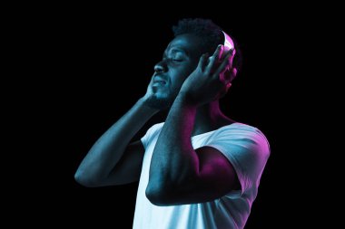 Genç Afro-Amerikalı adam karanlık arka planda, neon ışıkta izole edilmiş.