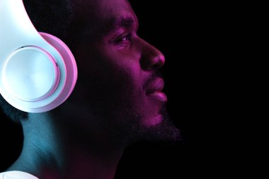 Genç Afro-Amerikalı adam, karanlık arka planda, neon ışıkta izole edilmiş.