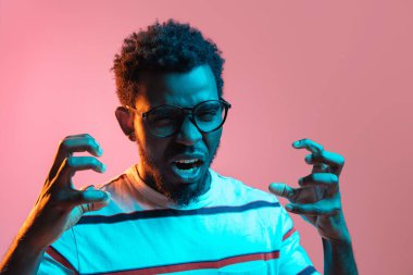 Genç Afro-Amerikalı adam pembe arka planda neon ışıkta izole edilmiş.