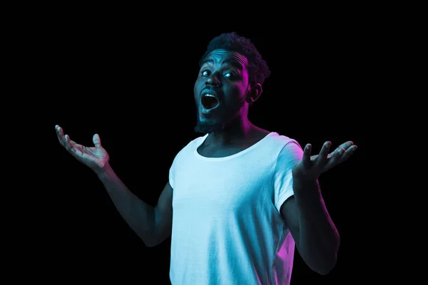 Fiatal afro-amerikai férfi elszigetelt sötét háttérrel neon fény — Stock Fotó