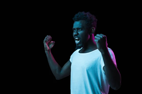 Young African-American man isolated on dark background in neon light — Stock Photo, Image
