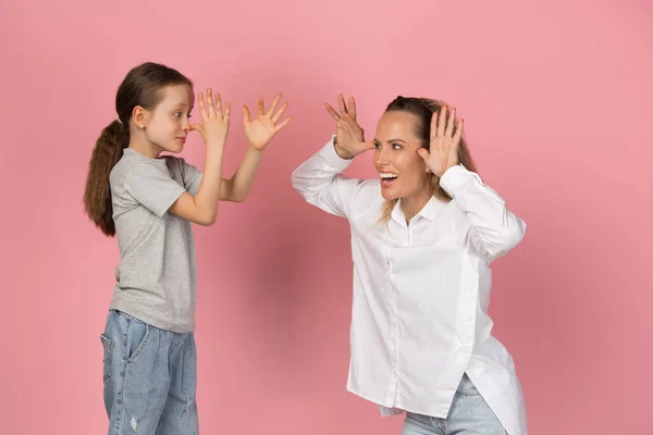 Jovem mulher e menina, mãe e filha isoladas sobre fundo rosa. — Fotografia de Stock