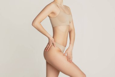 Kırpılmış ince, bronz tenli, iç çamaşırlı güzel bir kadın..