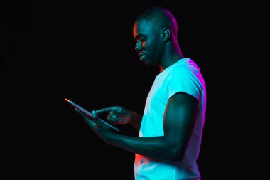 Genç Afro-Amerikalı adam karanlık arka planda, neon ışıkta izole edilmiş.