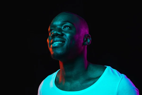 Young happy African-American man isolated on dark background in neon light — Stock Photo, Image