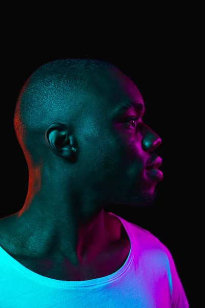 Young happy African-American man isolated on dark background in neon light — Stock Photo, Image