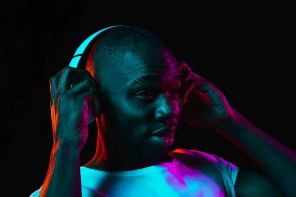 Young African-American man isolated on dark background in neon light — Stock Photo, Image