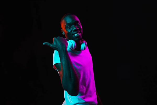 Genç Afrikalı bir adamın portresi, karanlık arka planda neon ışıkta izole edilmiş. — Stok fotoğraf
