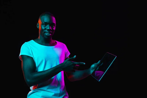 Young African-American man isolated on dark background in neon light — Stock Photo, Image