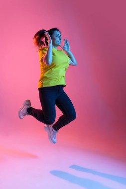 Güzel, mutlu bir kadının portresi. Pembe arka planda, neon ışıkta izole edilmiş.