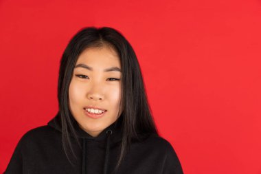 Kırmızı stüdyo arka planında izole Asyalı genç kadın portresi.
