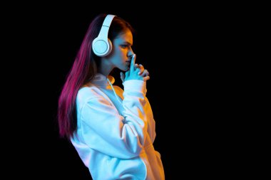 Kulaklıklı güzel bir kızın portresi karanlık arka planda izole edilmiş..