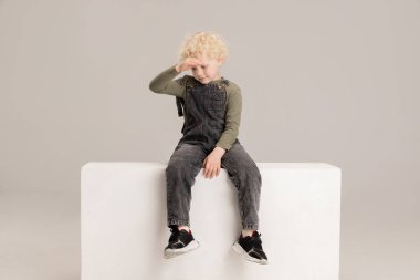 Kafkasyalı küçük bir çocuk gri stüdyo arka planından izole edilmiş bir kutuda oturuyor..