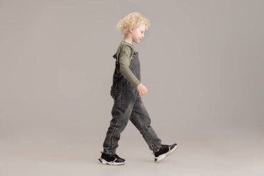 Kafkasyalı küçük albino çocuk gri stüdyo arka planında yalnız poz veriyor..