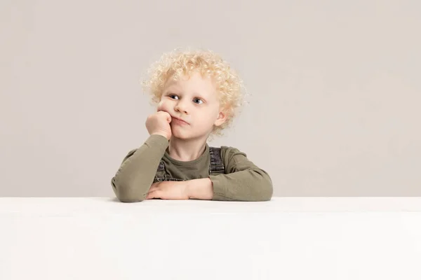 Un petit garçon caucasien posant isolé sur fond de studio gris. — Photo