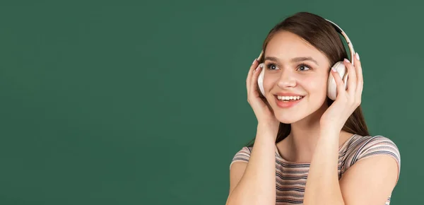 Jeune belle fille caucasienne dans les écouteurs isolés sur fond vert. — Photo