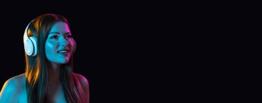 El ilanı. Kulaklıklı genç bir kız karanlık arka planda izole edilmiş..