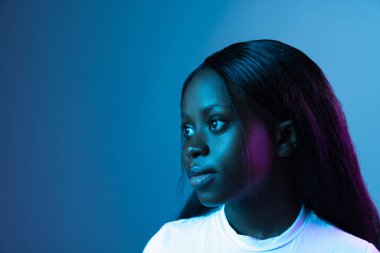 Genç bir Afrikalı güzel kız karanlık arka planda izole edilmiş karışık neon ışıkta..