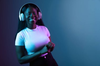 Genç Afrikalı güzel bir kızın portresi. Karanlık arka planda izole edilmiş. Karmaşık neon ışığında..