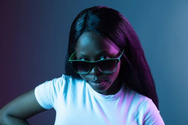 Genç Afrikalı güzel bir kızın portresi. Karanlık arka planda izole edilmiş. Karmaşık neon ışığında..