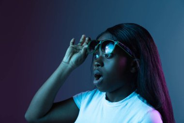 Genç Afrikalı güzel bir kızın portresi. Karanlık arka planda izole edilmiş. Karmaşık neon ışığında..