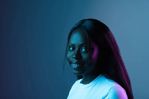 Porträt eines jungen afrikanischen schönen Mädchens isoliert über dunklem Hintergrund in gemischtem Neonlicht. — Stockfoto