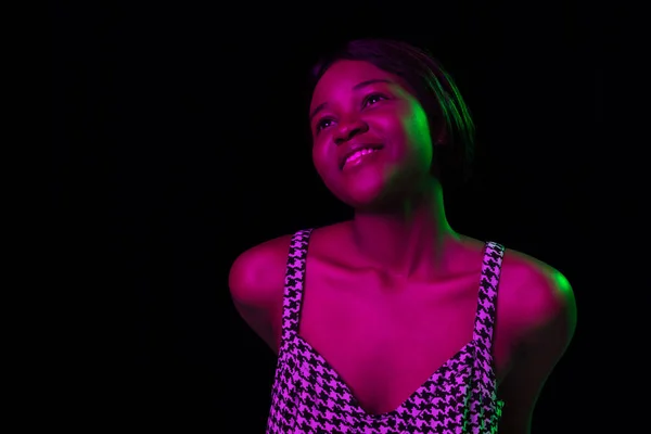 Одна молодая африканская красивая девушка изолирована на тёмном фоне в смешанном неоновом свете. — стоковое фото