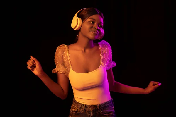 Молода африканська вродлива дівчина, ізольована на темному фоні у змішаному неоновому світлі.. — стокове фото