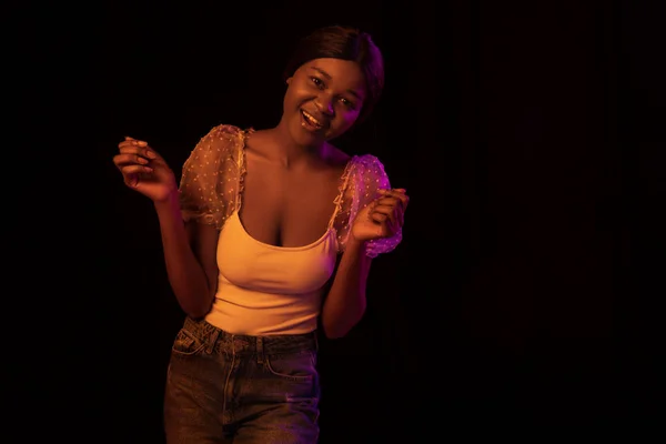 Porträt eines jungen afrikanischen schönen Mädchens isoliert über dunklem Hintergrund in gemischtem Neonlicht. — Stockfoto