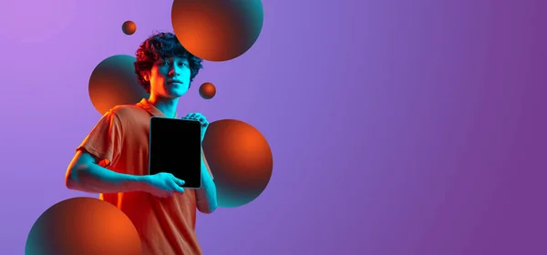 Portrait de jeune homme avec tablette numérique isolé sur fond violet dans la lumière néon. Dépliant — Photo