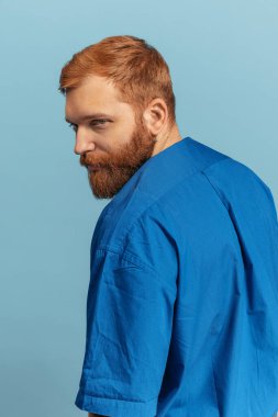 Mavi arka planda izole edilmiş genç kızıl saçlı ve sakallı adamın yakın plan portresi. Eras karşılaştırması