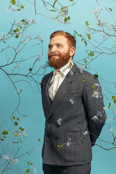 Portrait de jeune homme à la tête rouge et barbu agissant artiste célèbre isolé sur fond bleu floral — Photo