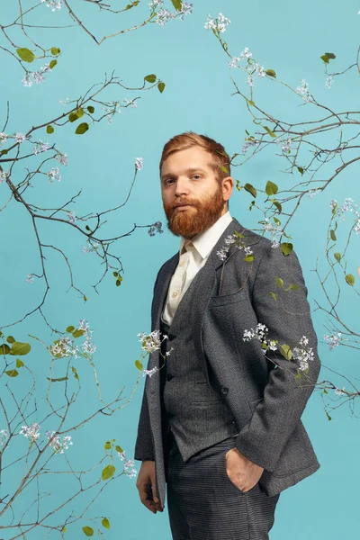 Portrait de jeune homme à la tête rouge et barbu agissant artiste célèbre isolé sur fond bleu floral — Photo