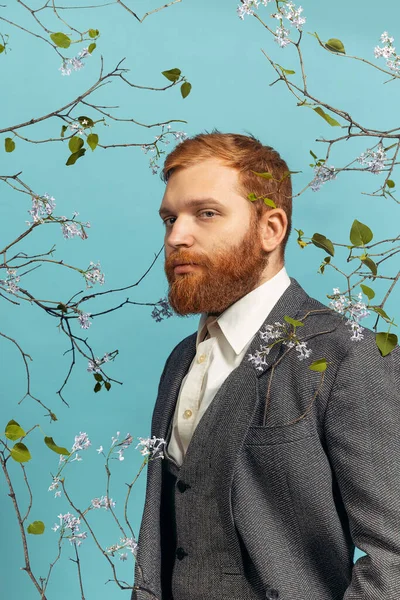 Gros plan portrait de jeune homme à la tête rouge et barbu agissant artiste célèbre isolé sur fond bleu floral — Photo