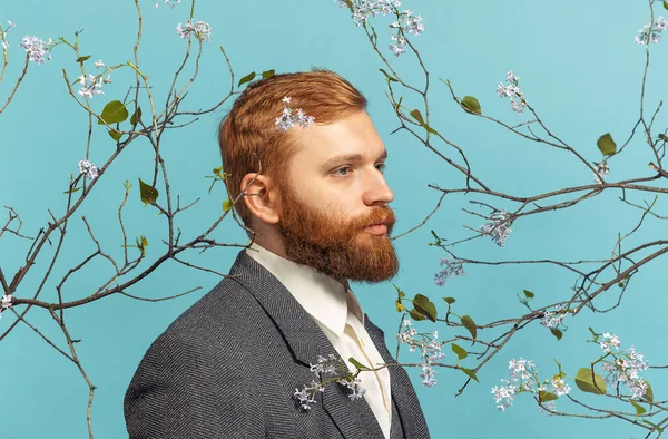 Gros plan portrait de jeune homme à la tête rouge et barbu agissant artiste célèbre isolé sur fond bleu floral — Photo